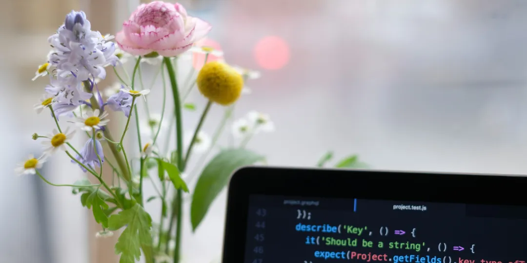 computer with programming code on screen and flower in background