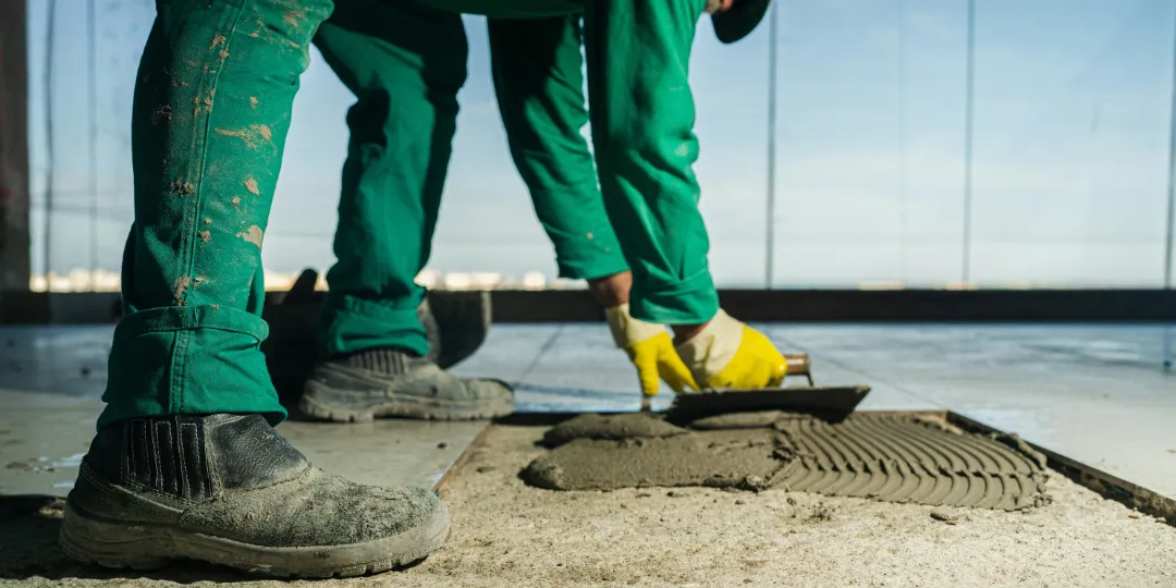 construction worker laying tiles on floor