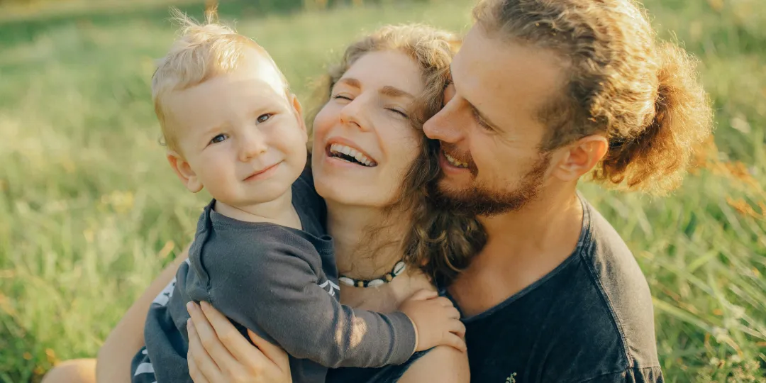 family hugging and smiling in a meadow