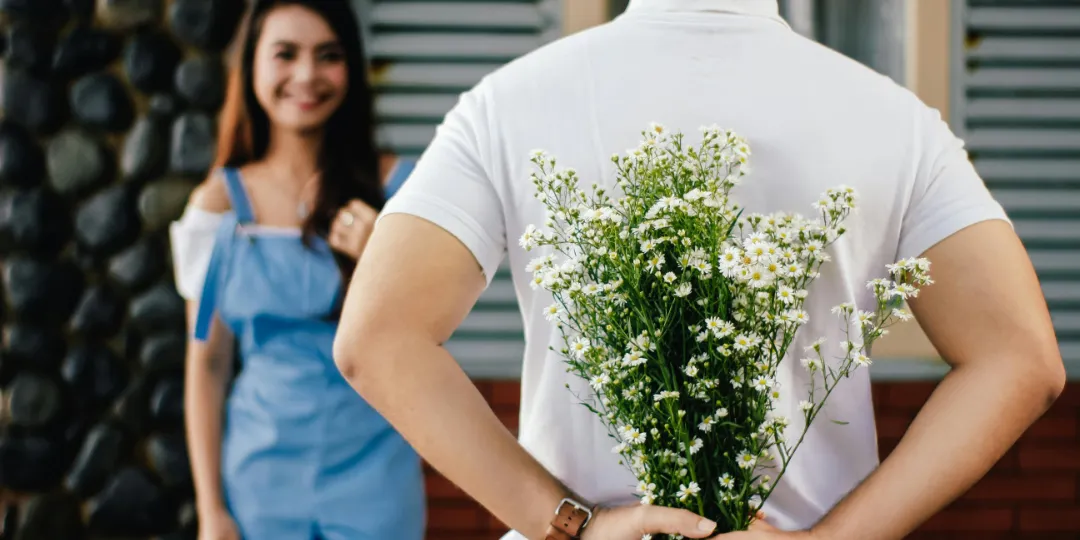 man holding flowers behind his back