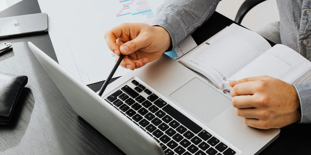 man looking at computer with open calendar on desk