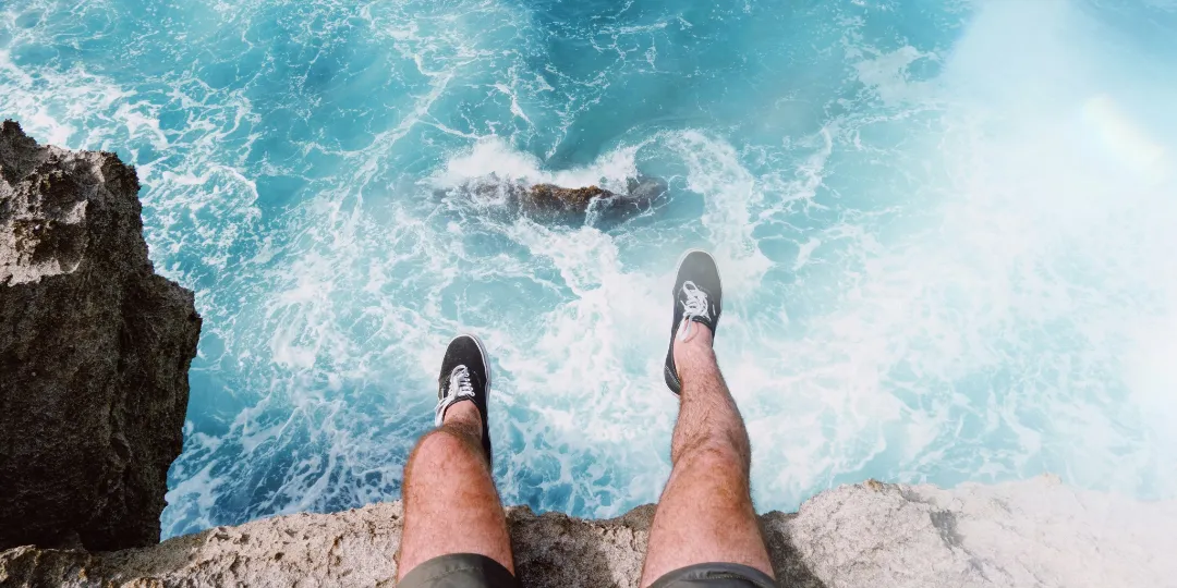 man sitting on rock with sea underneath