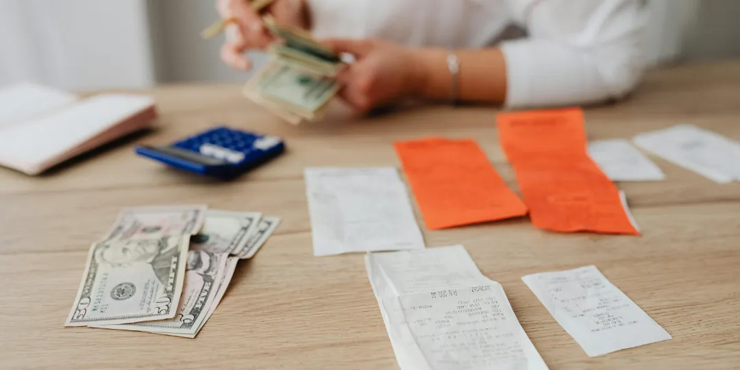 person counting money with receipts on table