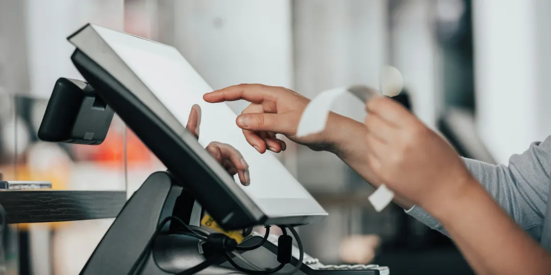 person holding receipt and typing on touchscreen