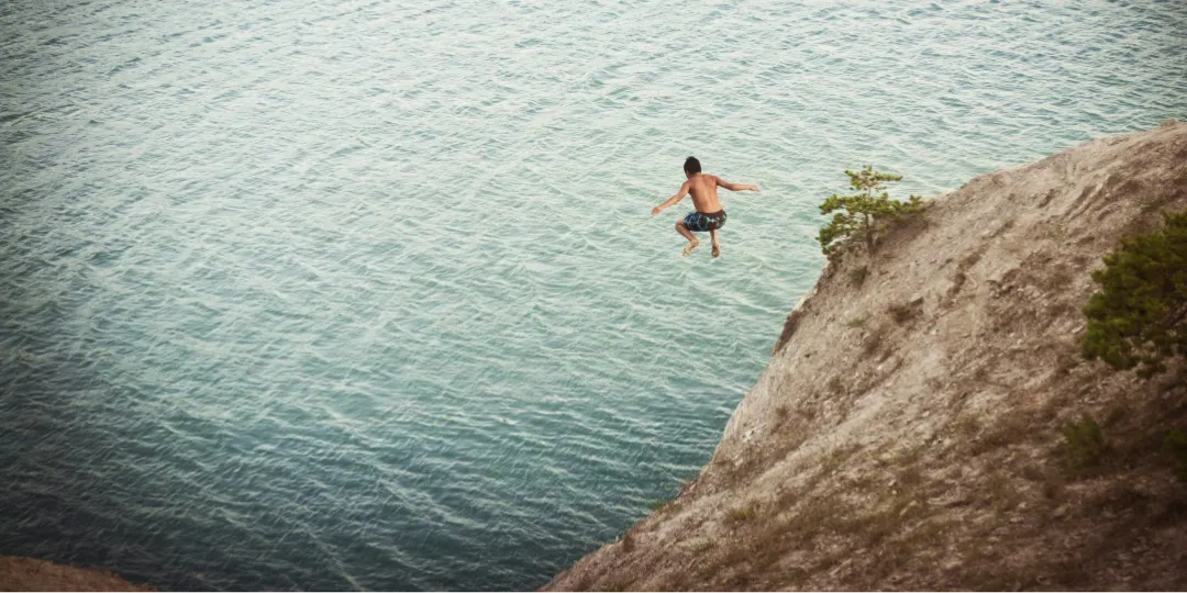 person jumping in water from a cliff