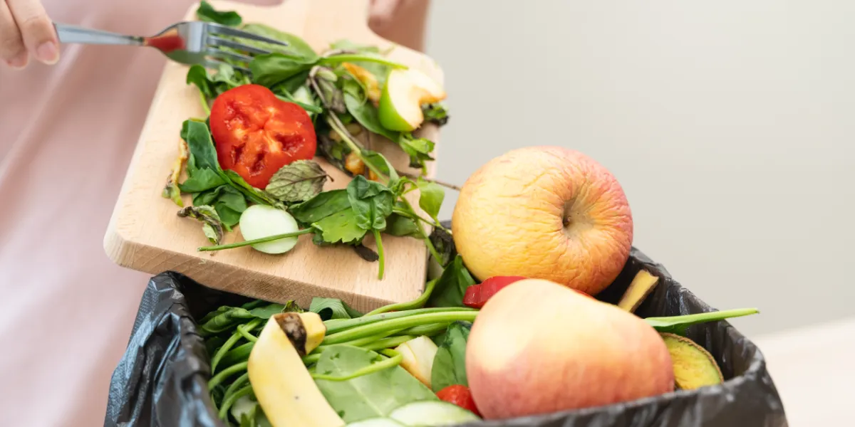 person scraping food waste into garbage can