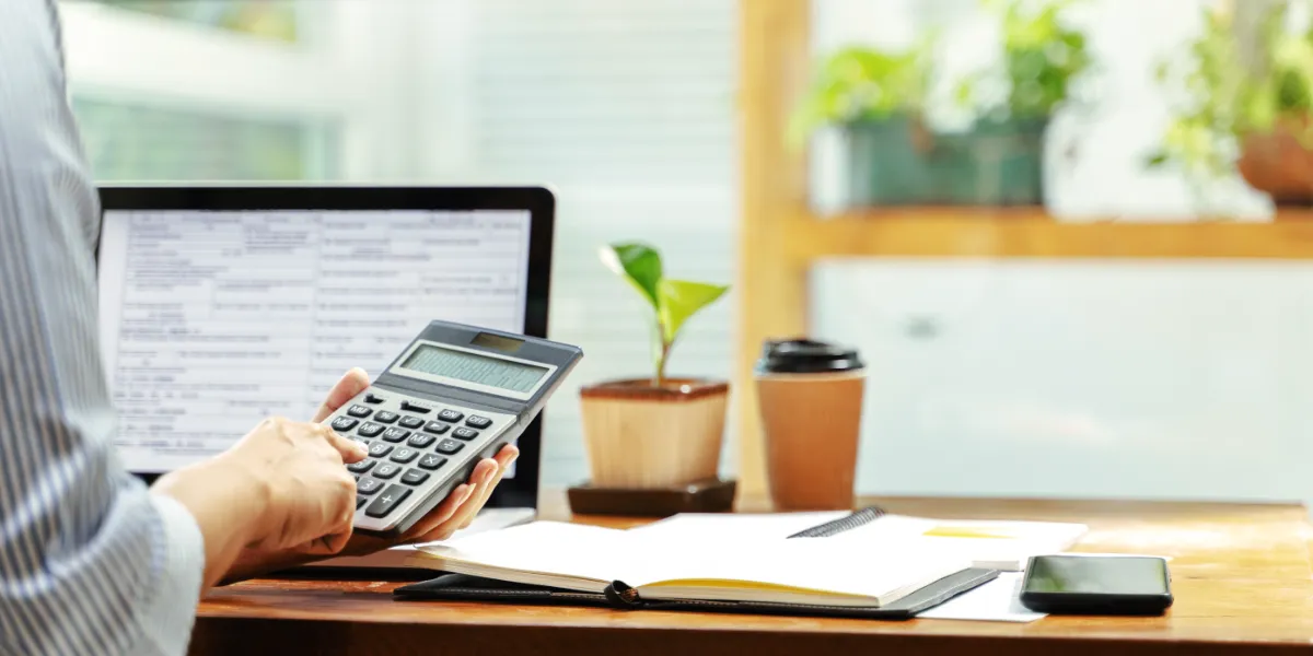 person typing on calculator while sitting in front of computer