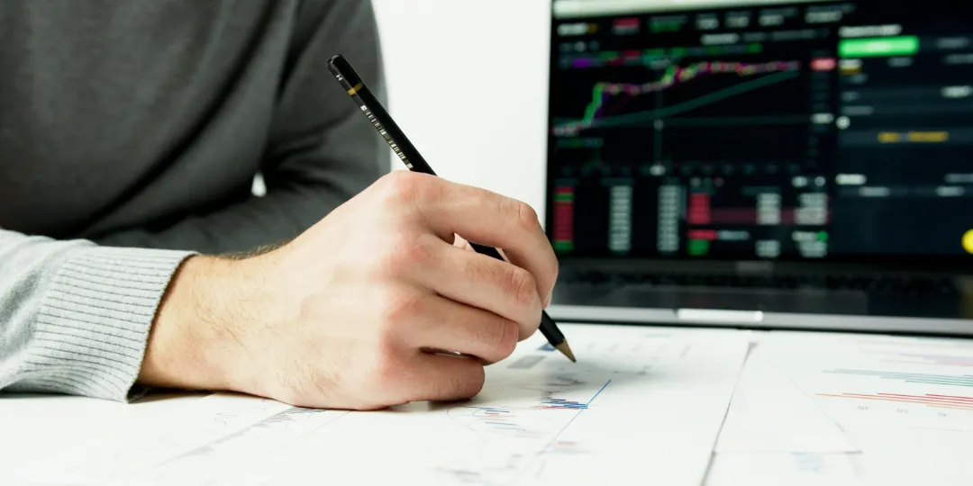 person using pencil to analyze stock charts