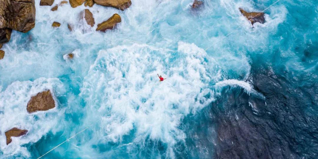 person walking a tightrope over the ocean