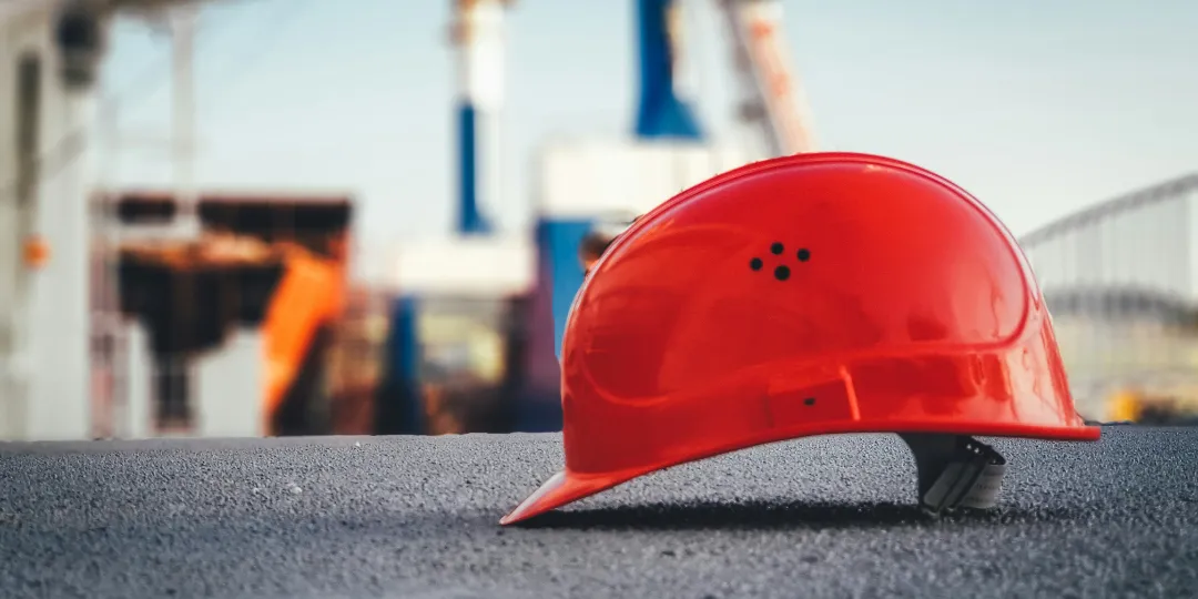 red construction worker helmet on pavement