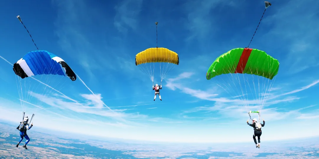 three parachute gliders in the air