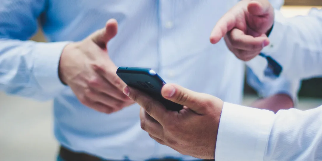 two business people discussing holding phone