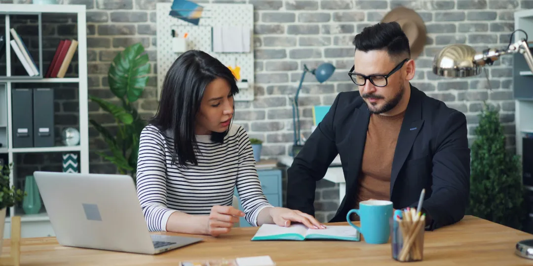 woman and man discussing over open notebook