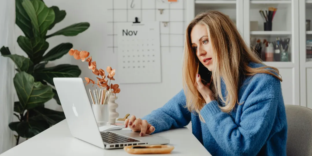 woman calling on the phone while looking at computer