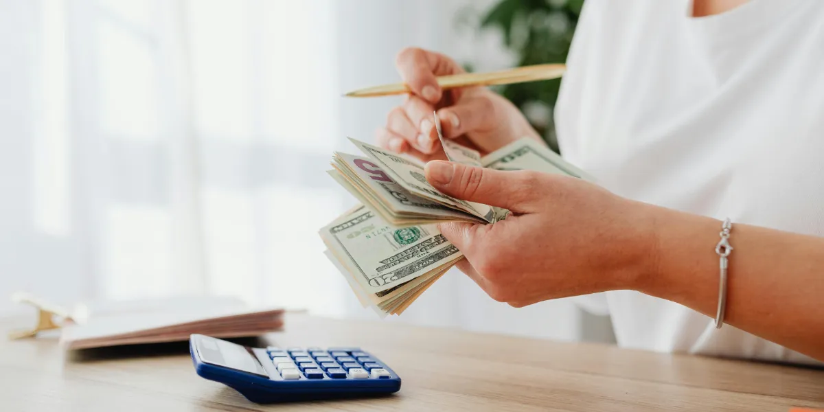 woman counting money with calculator on the table