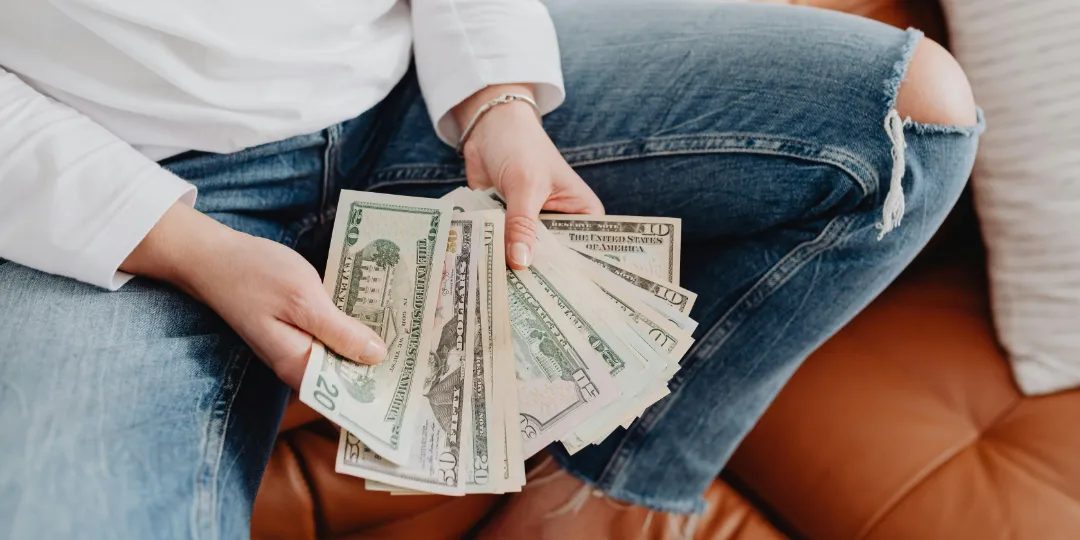 woman holding several dollar bills