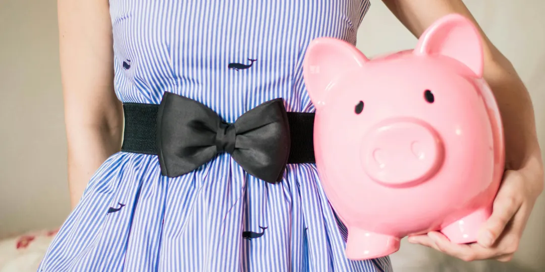 woman in dress holding pink piggy bank