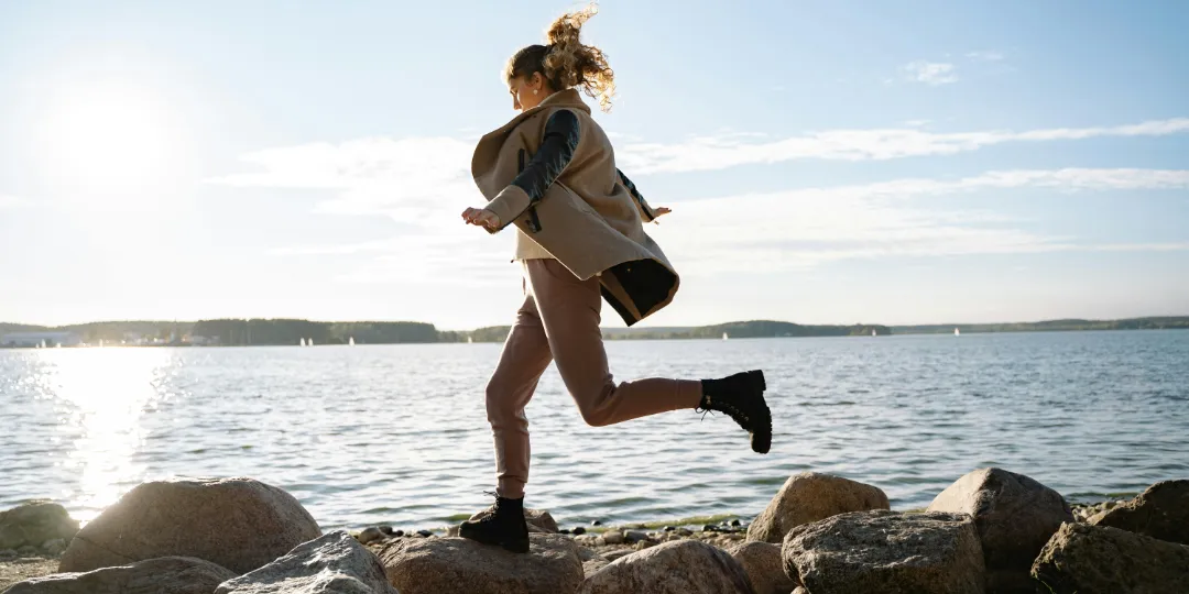 woman jumping from stone to stone