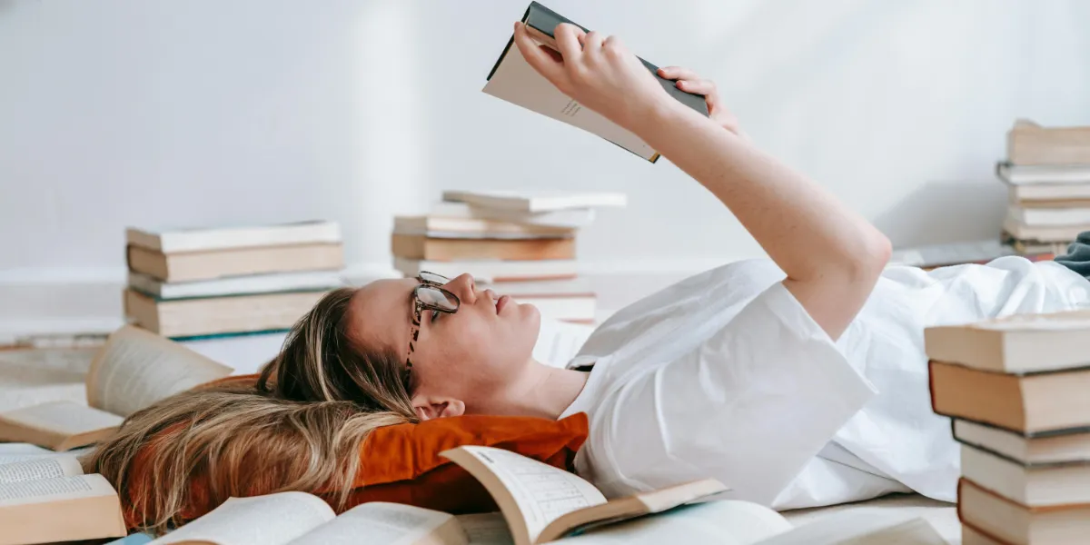 woman laying on the floor surrounded by books