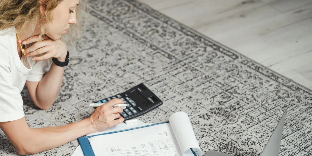 woman on the floor typing on calculator