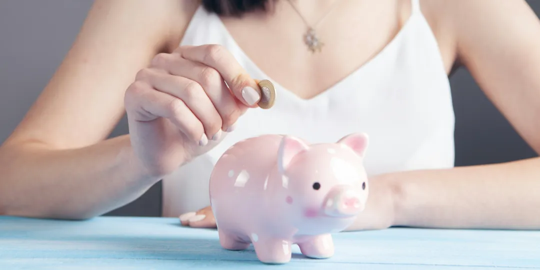 woman putting coin in piggybank