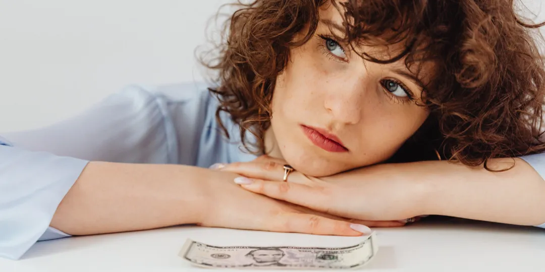 woman thinking with dollar bill in front of her