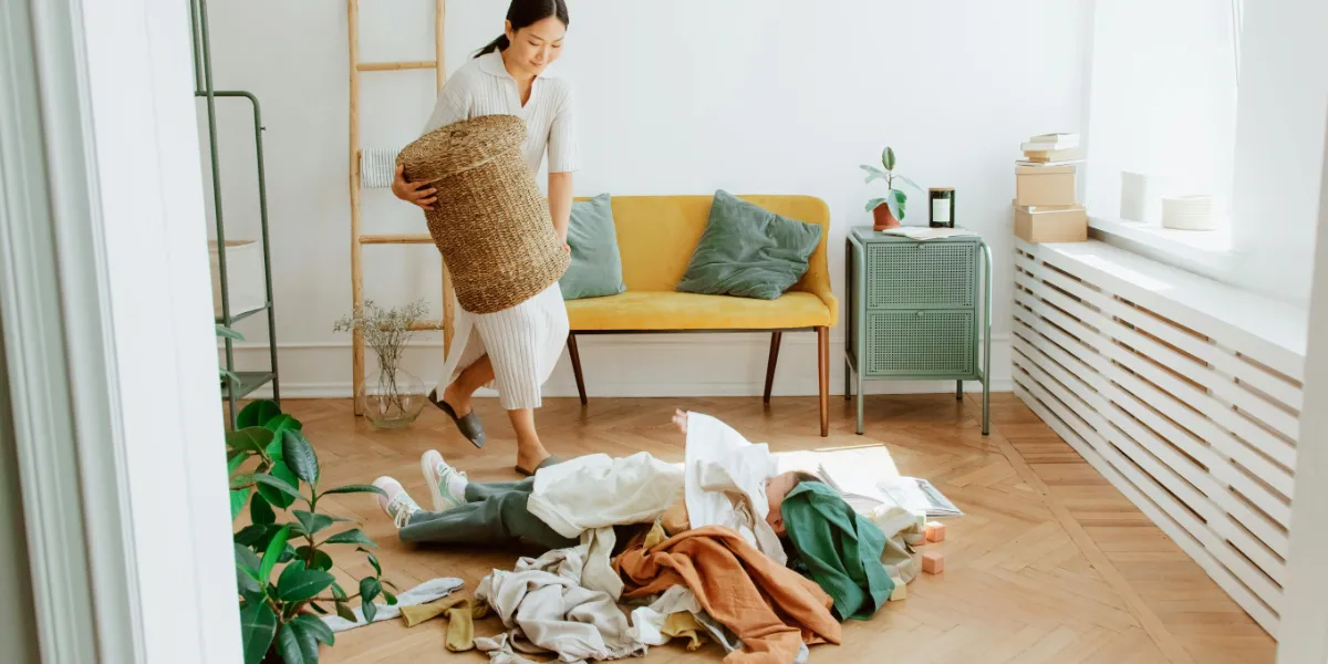 woman watching child playing with laundry